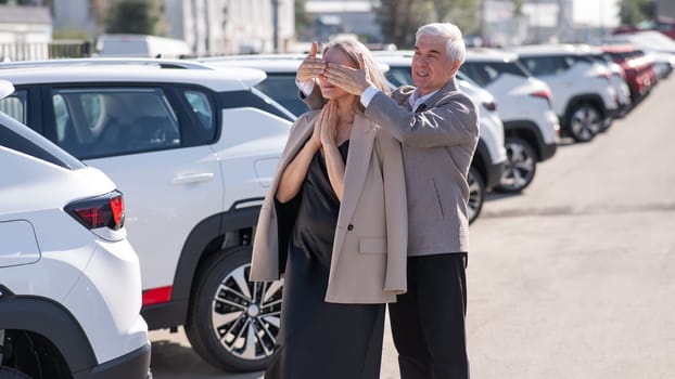 An elderly Caucasian man gives a new car to his beloved woman