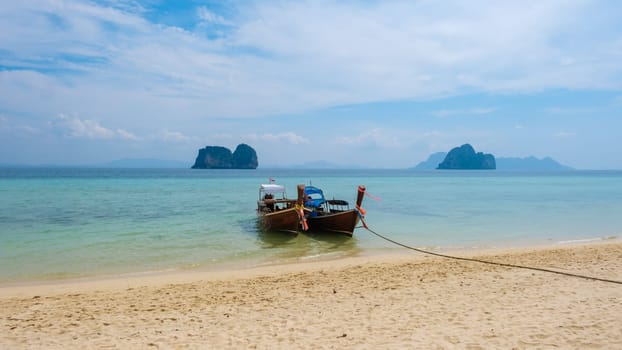 Longtail boats on the beach of Koh Ngai island with soft white sand, and a turqouse colored ocean, Koh Ngai Trang Thailand