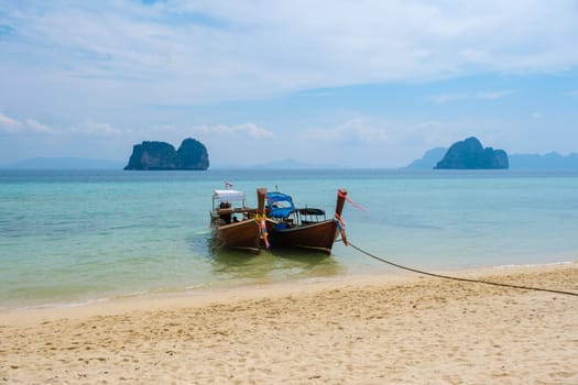 Longtail boats on the beach of Koh Ngai island with soft white sand, and a turqouse colored ocean, Koh Ngai Trang Thailand