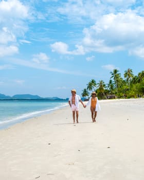 a young couple of caucasian men and a Thai Asian woman walking at the beach of Koh Muk Koh Mook Trang Thailand