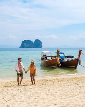 young couple, an Asian woman and European men on the beach of Koh Ngai island, soft white sand, and a turqouse colored ocean in Koh Ngai Trang Thailand