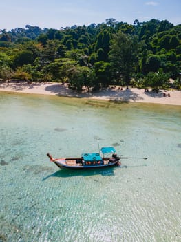 longtail boat in the turqouse colored ocean with clear water at Koh Kradan a tropical island in Trang Thailand, drone view from above