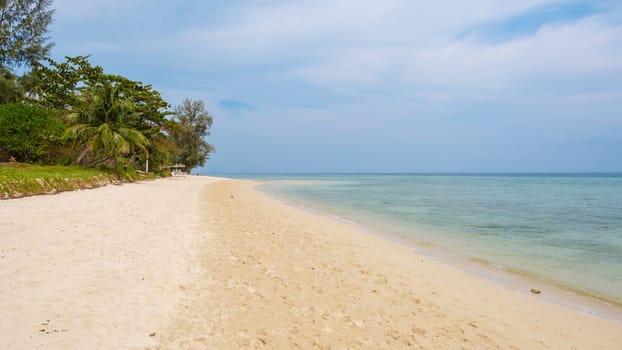 Drone aerial view at Koh Ngai island with palm trees soft white sand, and a turqouse colored ocean in Koh Ngai Trang Thailand