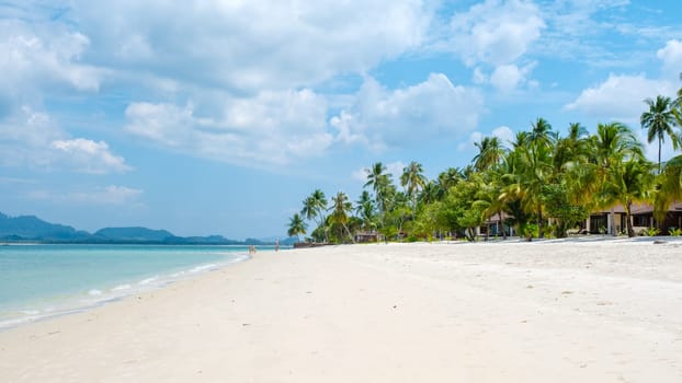 beach of Koh Muk a tropical island with palm trees and soft white sand, and a turqouse colored ocean in Koh Mook Trang Thailand