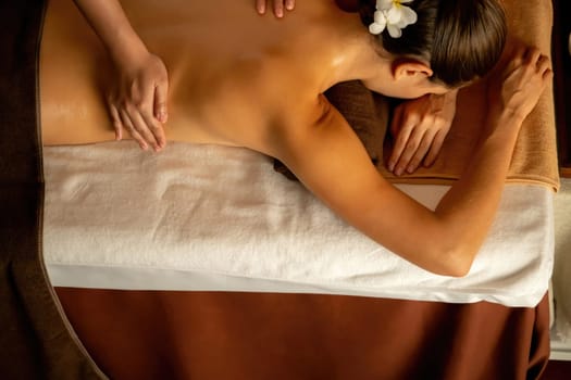 Caucasian woman customer enjoying relaxing anti-stress spa massage and pampering with beauty skin recreation leisure in warm candle lighting ambient salon spa at luxury resort or hotel. Quiescent