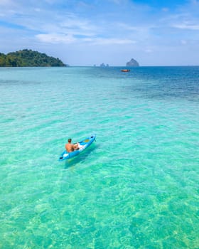 Young men in a kayak at the bleu turqouse colored ocean of Koh Kradan Thailand, a tropical island with a coral reef in the ocean, Koh Kradan Trang Thailand