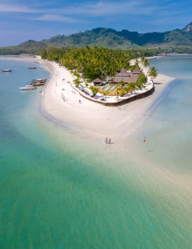 Drone aerial view at Koh Muk a tropical island with palm trees and soft white sand, and a turqouse colored ocean in Koh Mook Trang Thailand on a sunny day