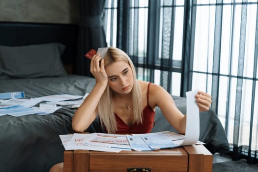 Stress worried young woman sit at table, as she pay bills online with credit card from financial debt problem, monthly expense and credit card debt. Over spending money lifestyle problem. Blithe