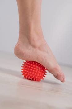 Close-up of a woman's foot on a massage ball with spikes