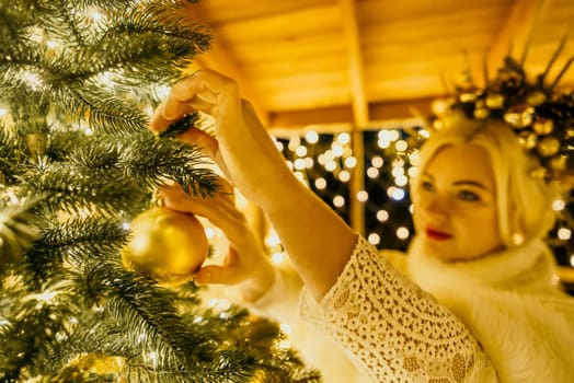 A Christmas tree with gold ornaments and lights. The tree is decorated with gold balls and is lit up with lights.