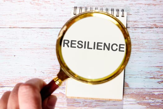 RESILIENCE text seen through magnifying glasses on a notepad