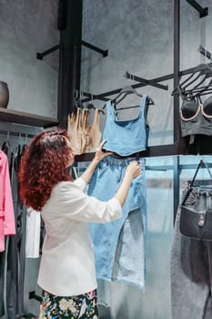 Shopping woman, women's fashion clothes in a store, boutique. Woman choosing clothes in a store.