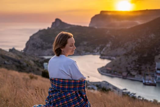 Happy woman on sunset in mountains. Woman siting with her back on the sunset in nature in summer. Silhouette