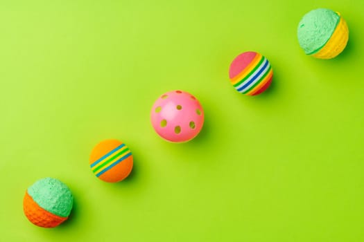 Colorful pet toys balls on green background close up
