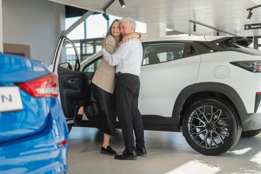 Mature Caucasian couple hugging with happiness while buying a new car