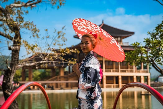 Asian girl in kimono and umbrella in Japanese theme park Hinoki Land in Chai Prakan District, Chiang Mai