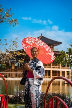 Asian girl in kimono and umbrella in Japanese theme park Hinoki Land in Chai Prakan District, Chiang Mai