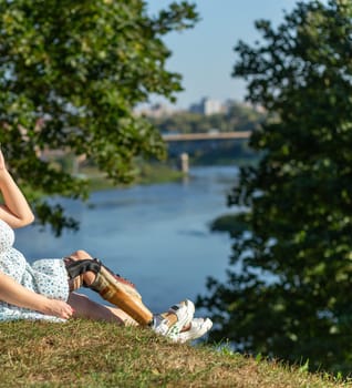 Beautiful young woman leg amputee in a dress walking in park near by river at sunny day. Life goes on no matter what.