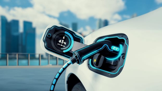 Electric car plug in with charging station to recharge battery display smart digital battery status hologram by EV charger cable on cityscape background. Future innovative energy sustainability.Peruse