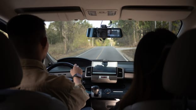 Rear view shot of young couple driving on country road. Traveling and vacation concept.