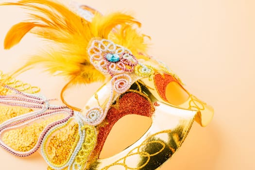 Close up golden venetian ball mask isolated on pastel background, Jewish Purim and Mardi Gras in Hebrew, holiday background banner design, Masquerade party, Happy Purim carnival decoration