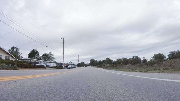 Santa Maria, California, USA-December 6, 2022-Vehicle navigates the streets of Morro Bay, California, during a cloudy winter day. The atmosphere is moody and serene as the overcast sky casts a soft light on the charming buildings and quiet streets of this coastal town.