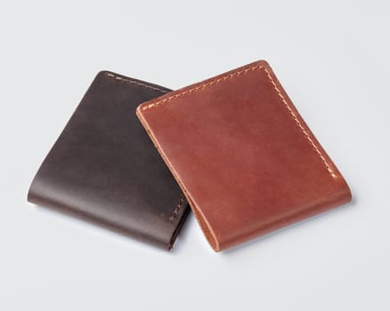 Pair of stylish slim mens brown leather wallets with decorative stitching and custom embossing on white background