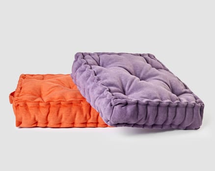 Two linen seat cushions in bright purple and orange colors casually arranged on white background, highlighting comfort and versatility in home design