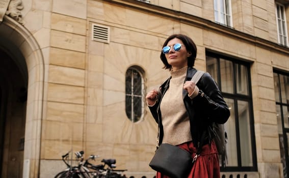 Attractive Woman In Sunglasses Walks In City With Backpack, Female Tourist Looking Around