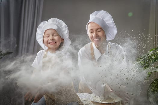 Cute oriental family with mother, daughter cooking in kitchen on Ramadan, Kurban-Bairam, Eid al-Adha. Funny family at cook photo shoot with flour. Pancakes, pastries, Maslenitsa, Easter