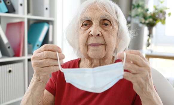 Elderly Woman Puts On Protective Medical Mask On Face