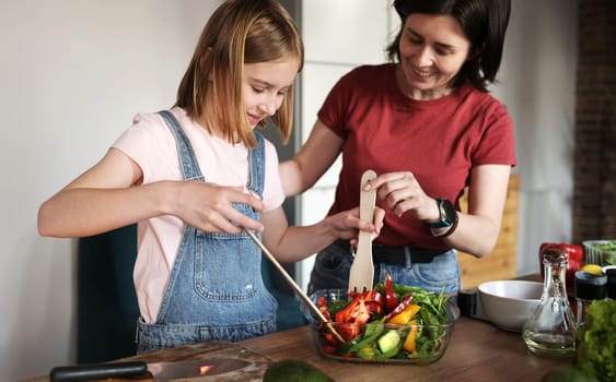 Beautiful Little Girl With Her Mother Cooking A Healthy Fresh Vegetable Salad In The Kitchen, Mother Teaches Her Daughter To Cook A Healthy Food