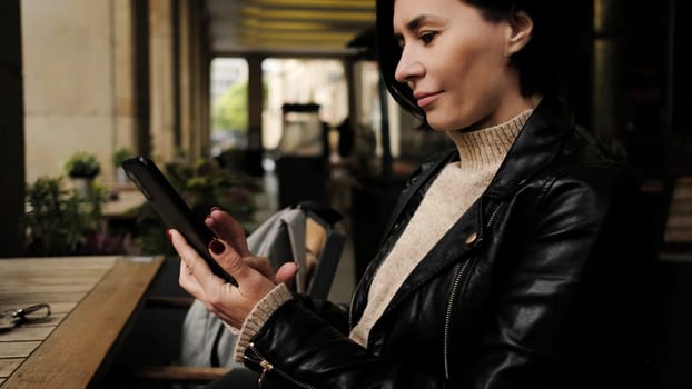 Attractive Woman Sits In Cafe, Using Smartphone To Type Message On Social Media, Waiting For Waiter