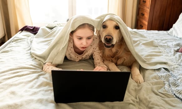 Joyful Little Girl Playing With Golden Retriever Dog, Covered By Blanket And Working With Laptop