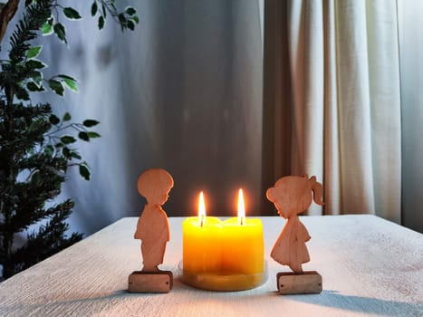 Wooden toys of boy and girl with yellow candles. Couple in love on Valentine's Day. Celebration of love and friendship. Card, background
