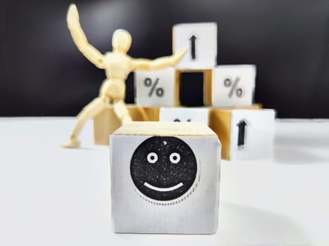 Wooden cubes in a column and row with white signs with a smiley sign, an arrow, a percentage. The concept of positivism. Positive thinking leads to the achievement of results and profits