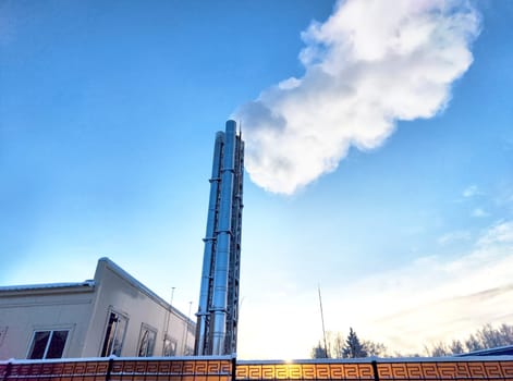Air pollution by smoke coming out of two factory chimneys. White clouds of smoke against a blue sky background