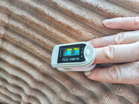 Close up of hand with a pulse oximeter on the finger.