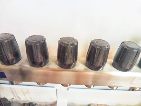 Close-up of plastic taps, valves, regulators on underfloor heating pipes and water standing in a row