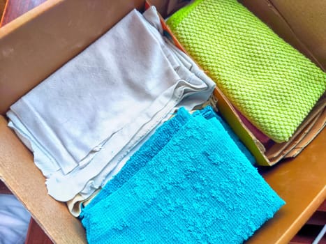 Old rags and eco-friendly cleaning cloths neatly arranged in a cardboard box. Old rags and things for cleaning and cleanliness in the house. Eco-friendly use of recyclables