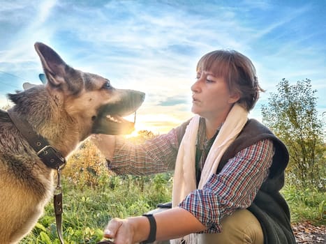Adult girl with shepherd dog taking selfies in field. Middle aged woman and big shepherd dog on nature. Friendship, love, communication, fun, hugs