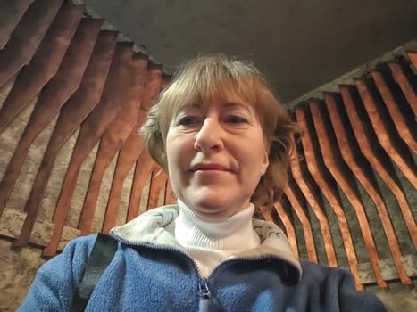 Portrait of 40-year-old woman with sport blue sweater. middle-aged blonde woman on the background of wooden slats in room