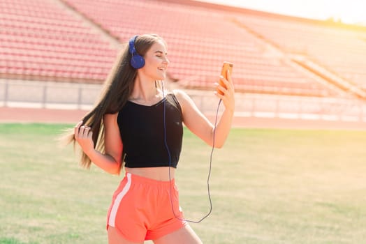 Young, beautiful girl athlete in sportswear is training and running, stretching at the stadium