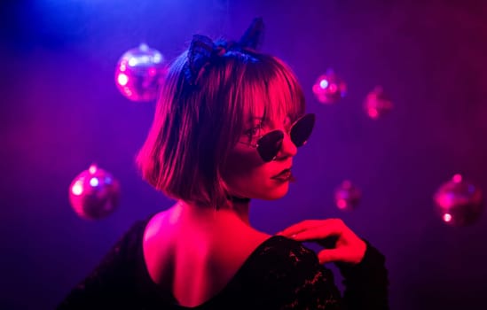 Portrait of young pretty woman in neon light. Pussy cat costume for halloween party. Sexy elegant lady with sunglasses and lace ears. High quality 4k footage