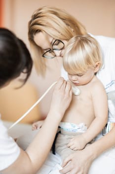 Small child being checked for heart murmur by heart ultrasound exam by cardiologist as part of regular medical checkout at pediatrician