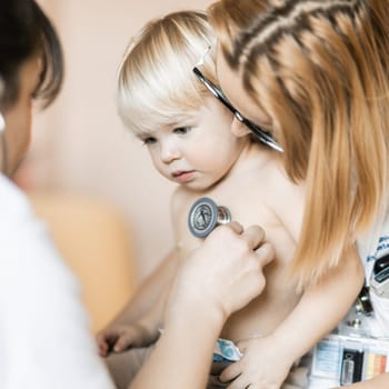 Doctor holding stethoscope and listening to child's heartbeat. Regular checkout at pediatrician at clinic or hospital. Healthcare and medical concept
