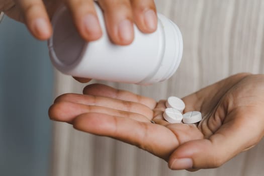 The white plastic bottle containing medicine is being poured into the hand for medical and healthcare concept