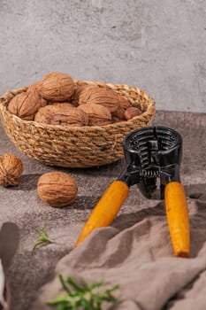 Basket with walnuts and hazelnuts and a nut cracker on a rustic kitchen counter.