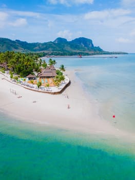 top drone view at Koh Muk a tropical island with palm trees and soft white sand, and a turqouse colored ocean in Koh Mook Trang Thailand