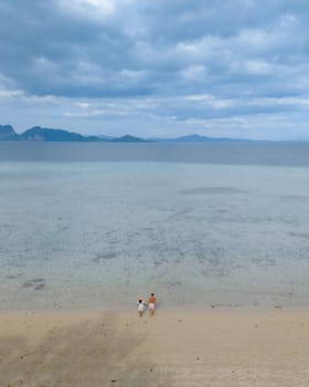 a couple on a boat trip to Koh Kradan a tropical island with palm trees soft white sand, and a turqouse colored ocean in Koh Kradan Trang Thailand, a popular island for snorkeling trips from koh lanta